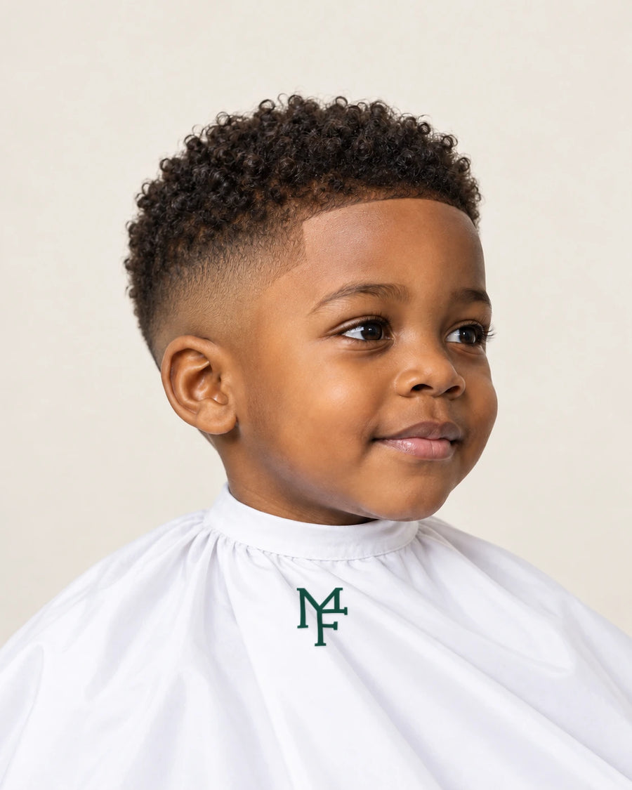 Illustration of a child with a coily top and taper fade, wearing a white cape with the emerald Miami Fades crest