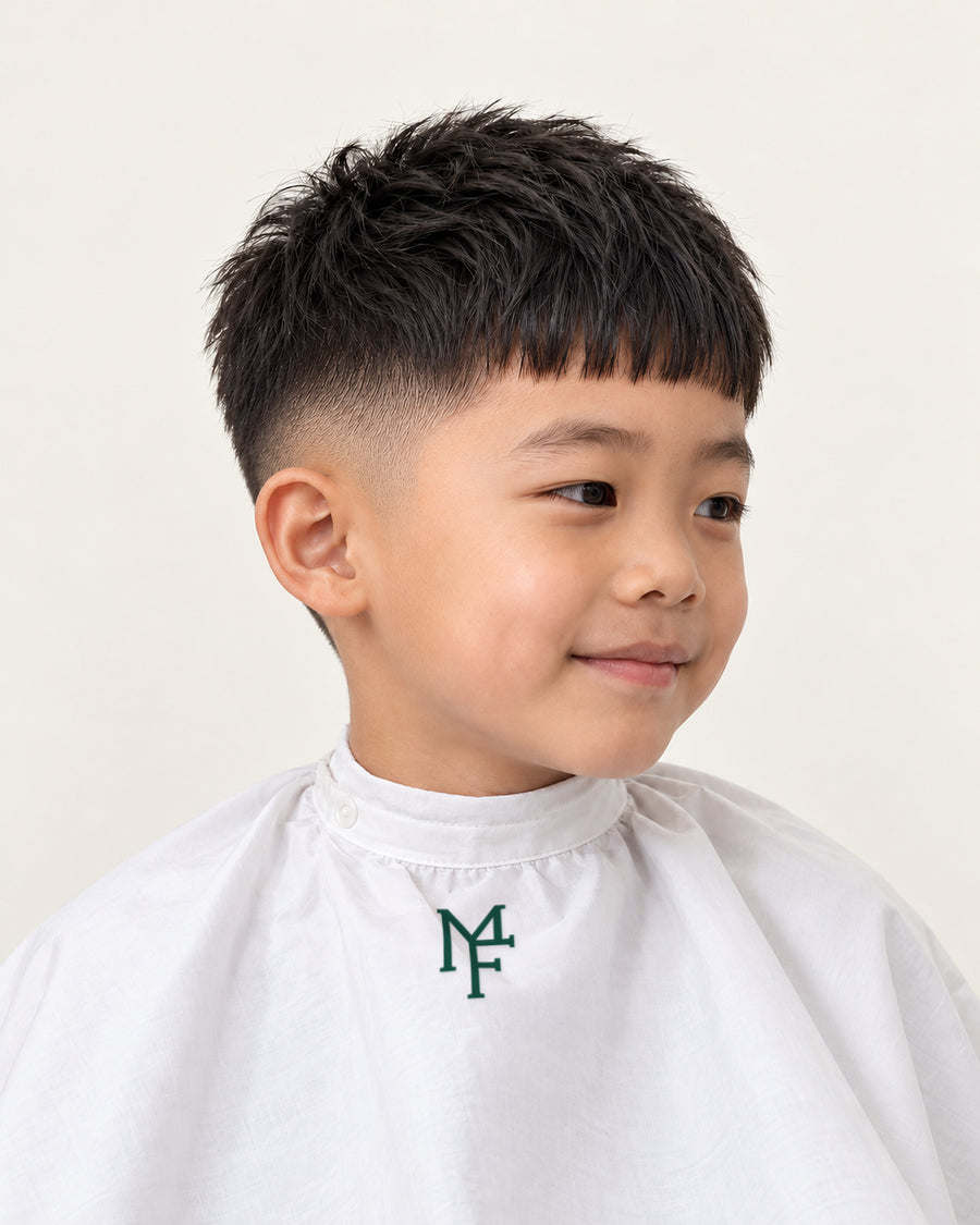 Illustration of a child with a crop fringe and mid fade, wearing a white cape with the emerald Miami Fades crest